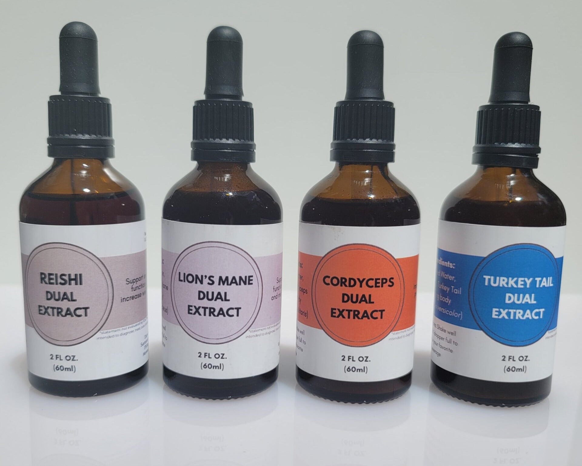 Four bottles of dual extract tinctures with droppers on a white background